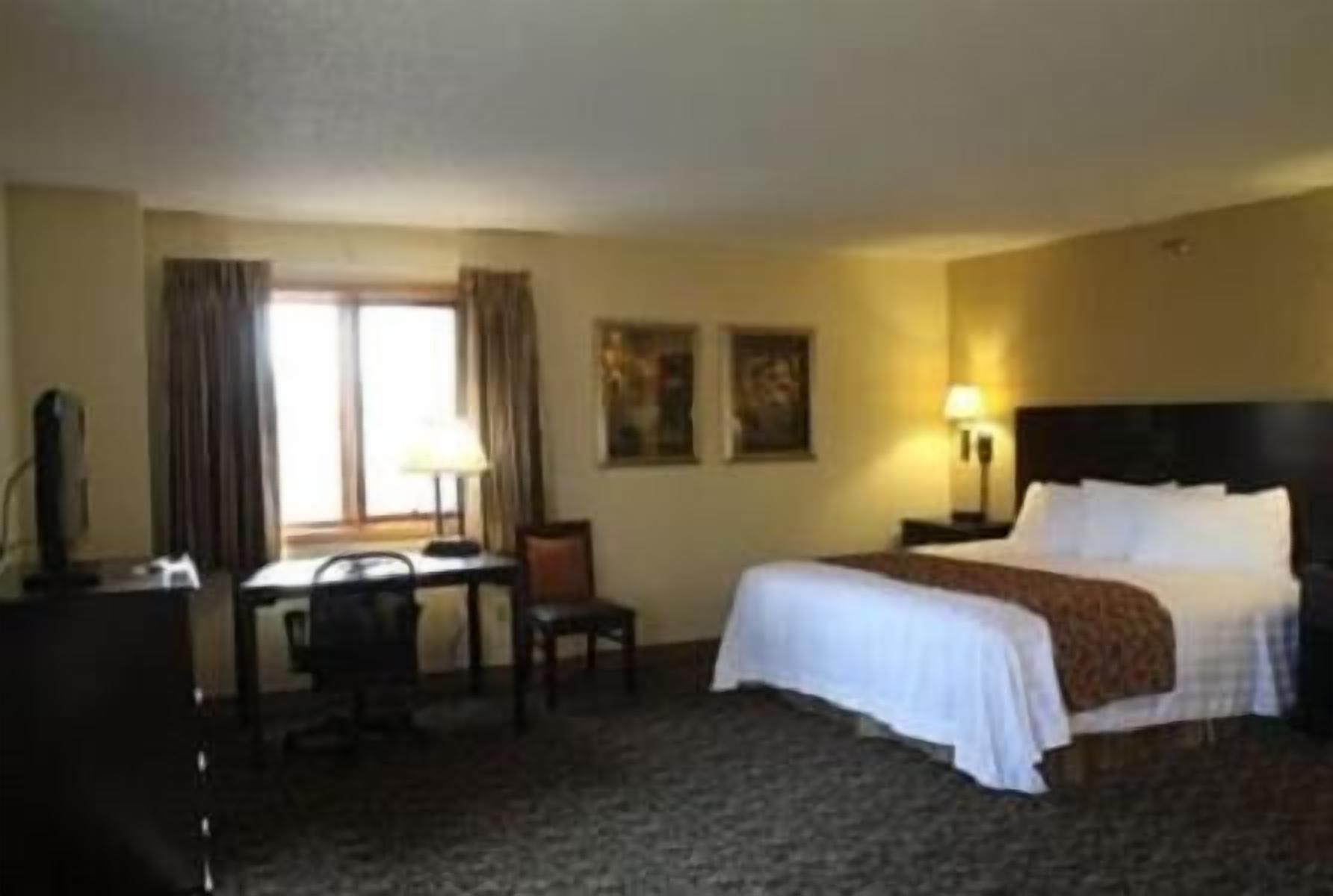Ein Hotelzimmer mit Bett, Schreibtisch, Stuhl und Lampe.