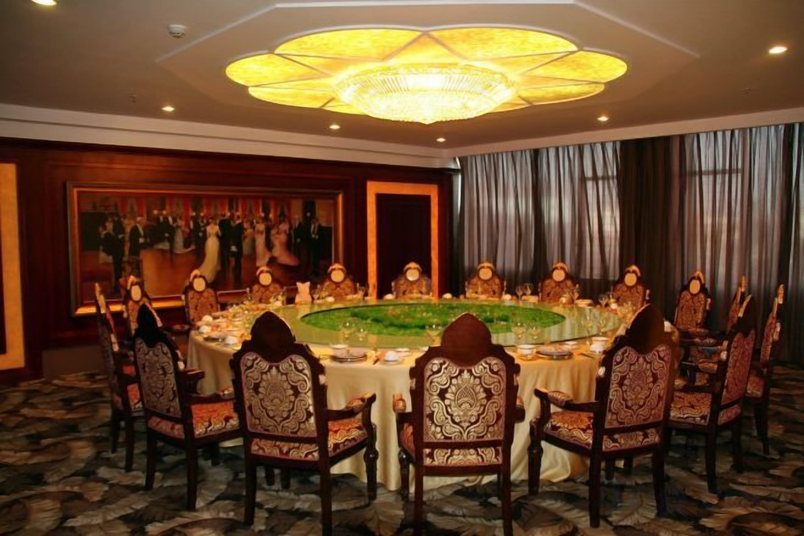 Uma sala de conferências com uma mesa redonda, cadeiras e um candelabro.