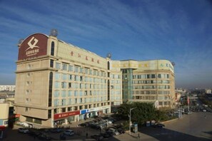 A multi-story hotel with a prominent red and white sign, a parking lot, and a clear sky. - Plateau Pearl Hotel (Kunming Yongzhong Road) (Kunming)