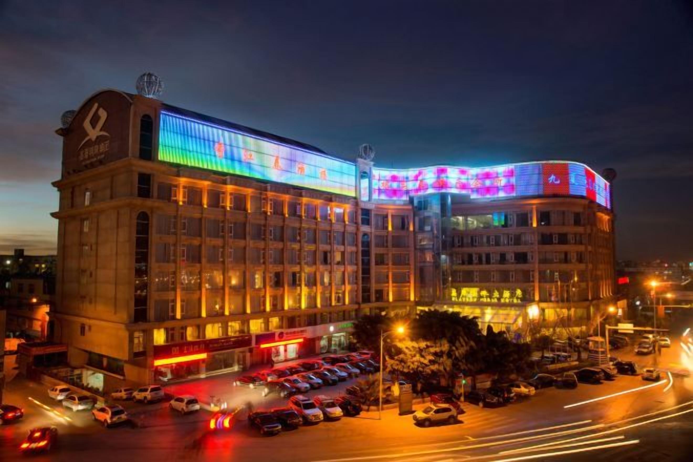 A multi-story hotel with a prominent curved corner and illuminated signage.