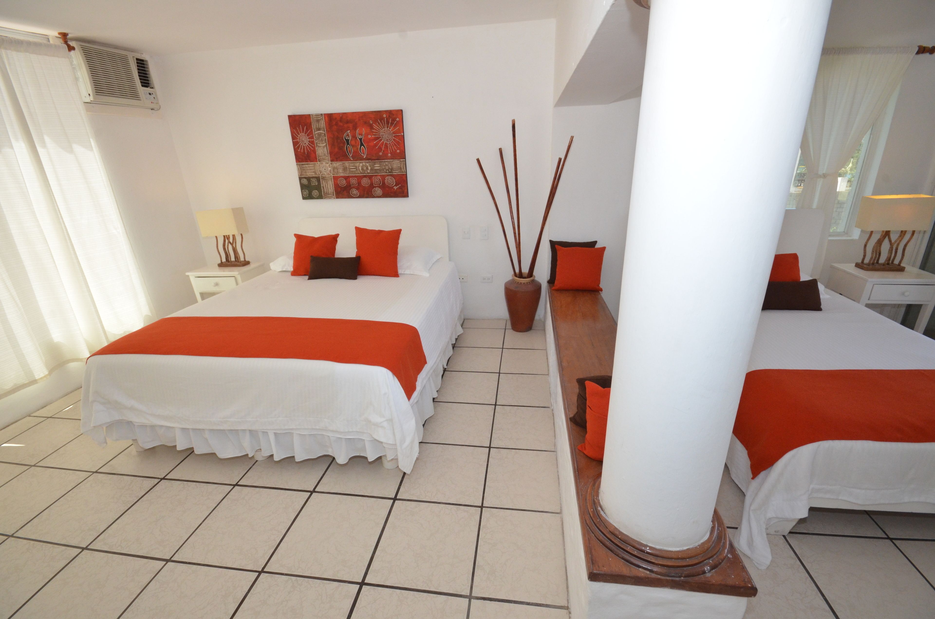 Habitación de hotel con dos camas, un ventanal grande, una obra de arte colgada en la pared y un jarrón decorativo.