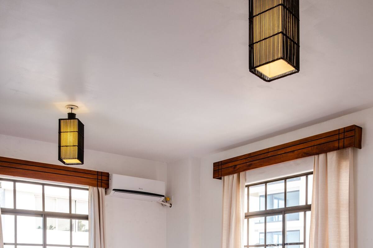 Une chambre d’hôtel avec un grand lit, deux tables de chevet avec des lampes, une fenêtre avec des rideaux et un luminaire au plafond.