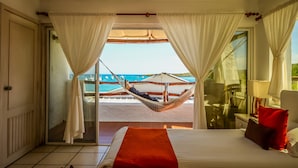 Ein Schlafzimmer mit Bett, einem roten Kissen und Meerblick durch ein Fenster.