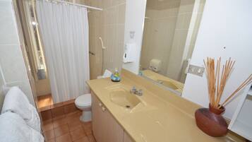 Une salle de bain avec un lavabo beige, des toilettes blanches et un espace douche.