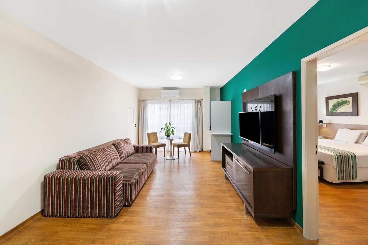 A modern living room with a sofa, a TV, and a dining area with a table and chairs.