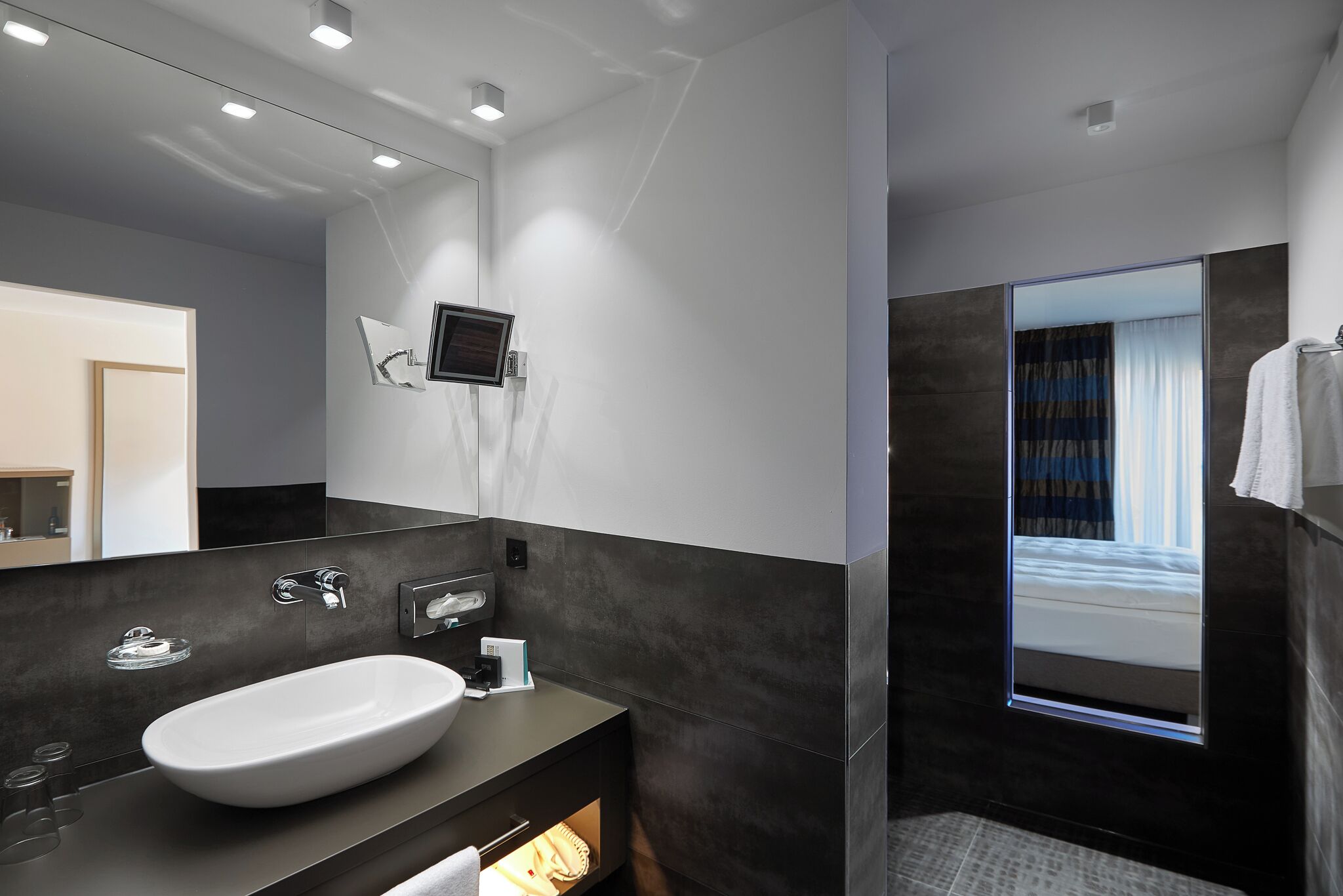 Un baño moderno con un espejo grande, un lavabo blanco y una zona de ducha.
