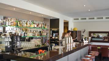 Eine Bar mit einer langen Theke, Hockern und Regalen voller Flaschen.
