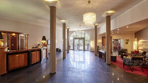 A spacious lobby with a reception desk, large columns, a chandelier, and seating areas. - Hotel Schloss Reinach (Freiburg im Breisgau)