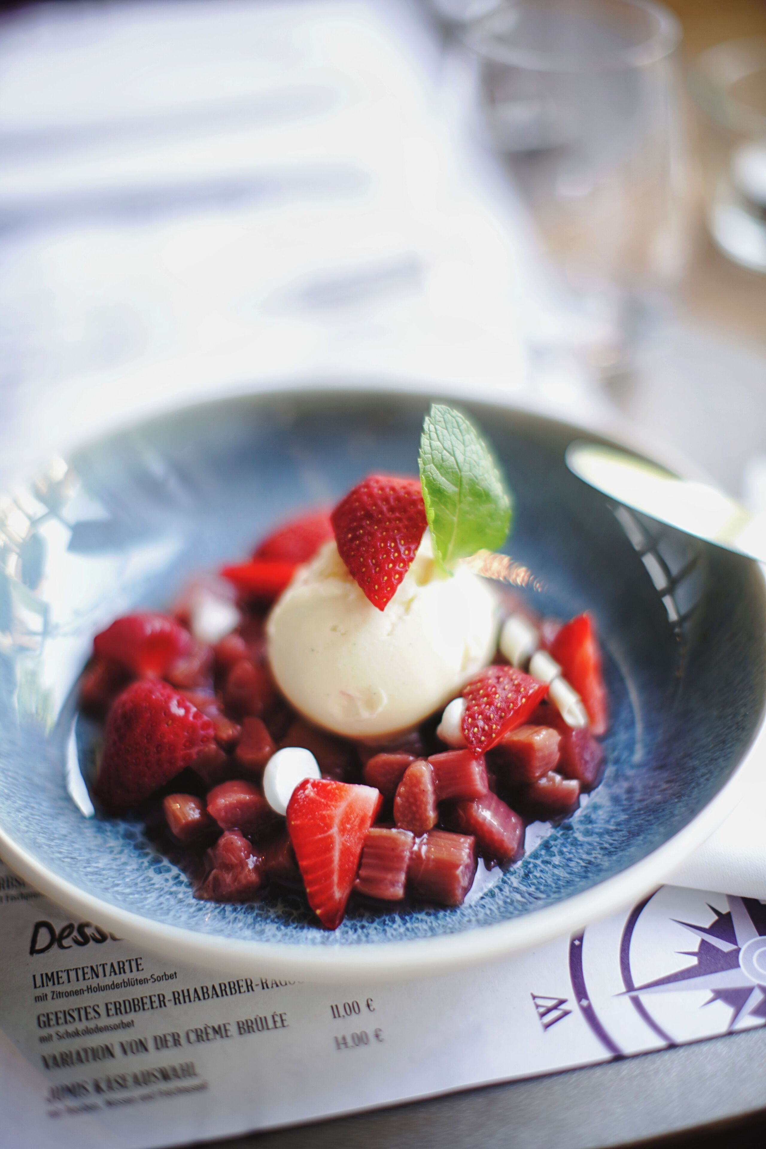 Un plato de postre con helado, fresas y menta.