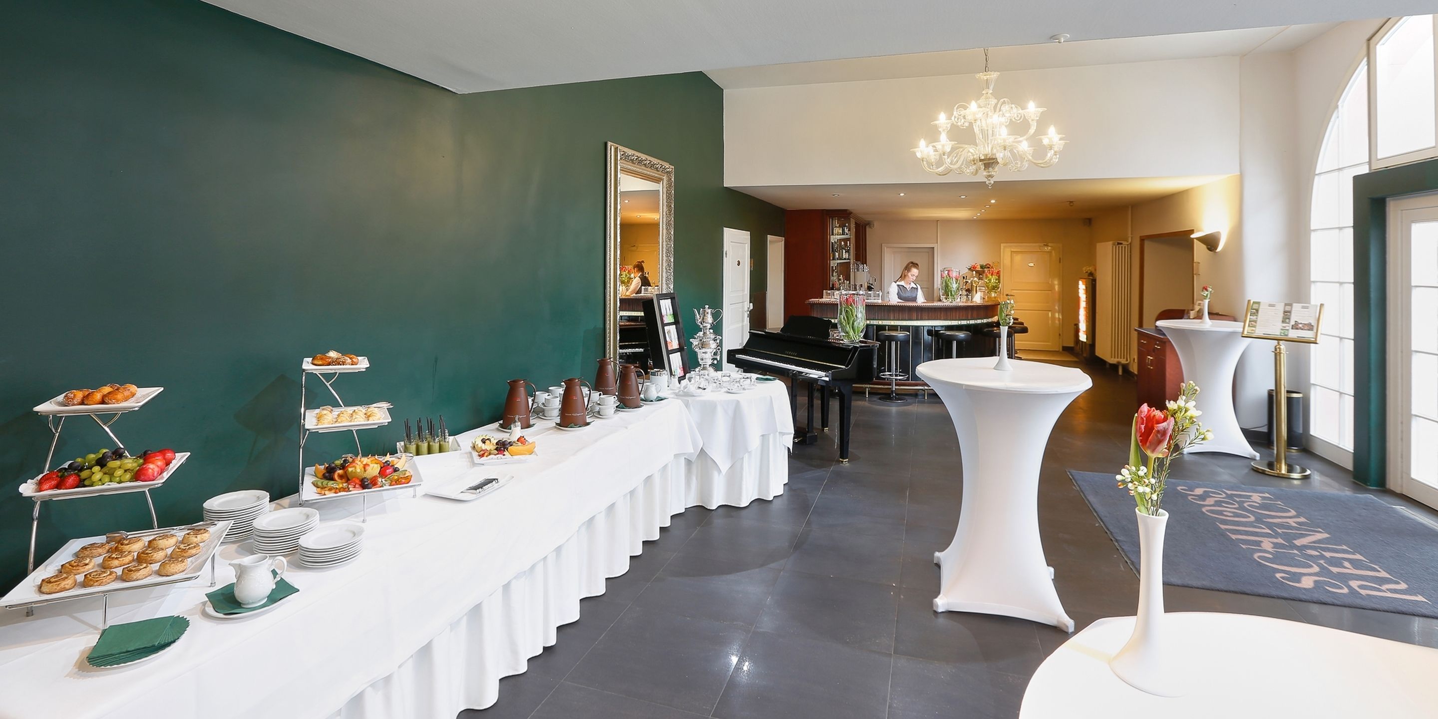 Ein reichhaltiges Buffet mit verschiedenen Speisen und einem Klavier im Hintergrund.