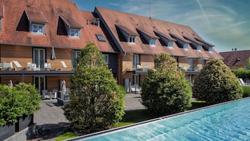 A modern hotel with a swimming pool, multiple balconies, and a well-maintained garden.