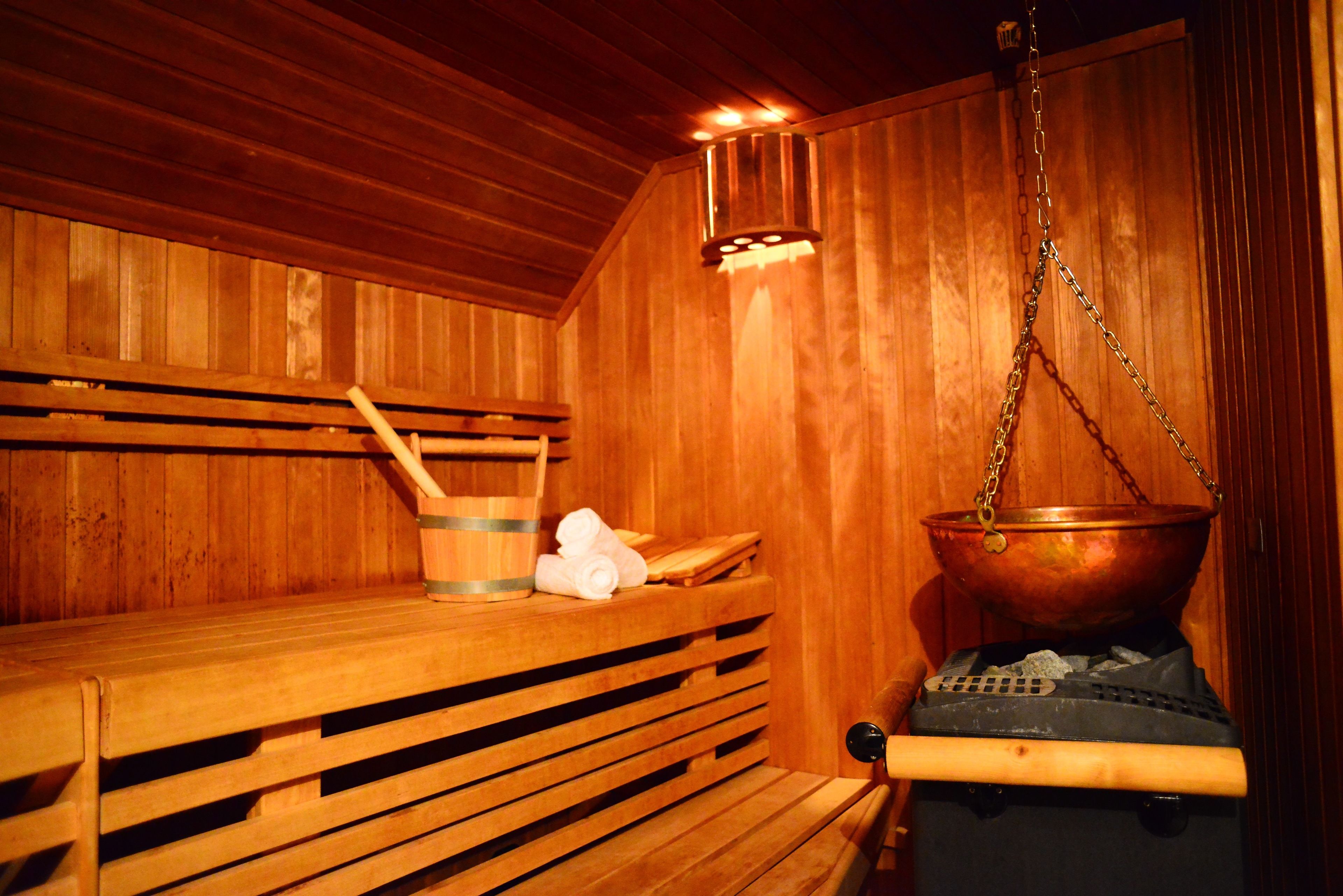 Un sauna en bois, avec un banc, un seau et un grand récipient en cuivre.