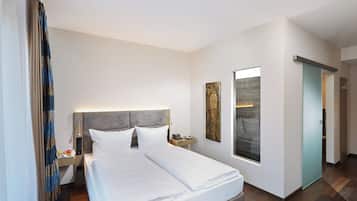 Habitación de hotel con cama, mesita de noche, lámpara, una obra de arte y vistas al exterior.