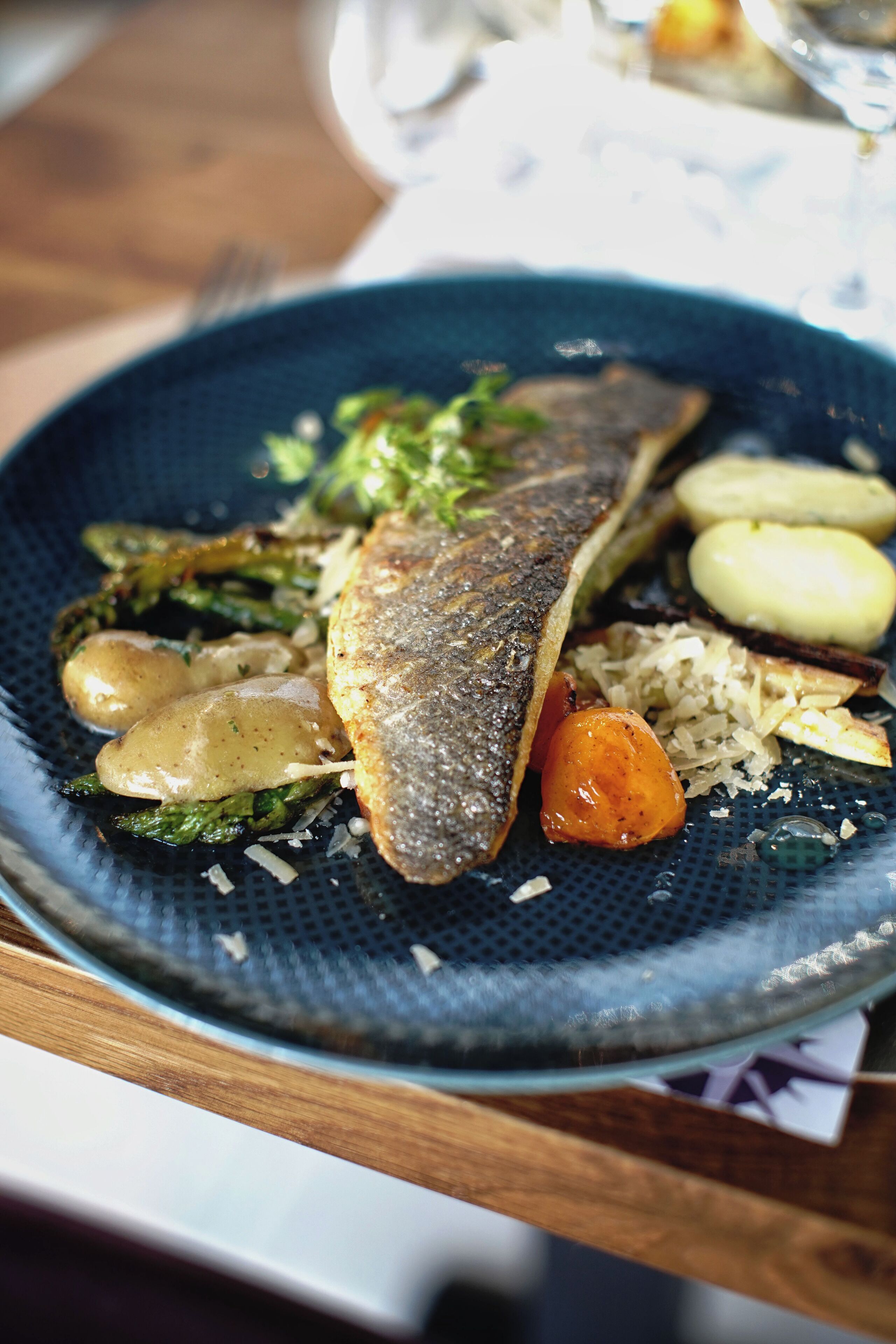 Un plato de comida con pescado, verduras y papas.