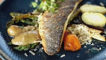 Un plato de comida con pescado, verduras y papas.