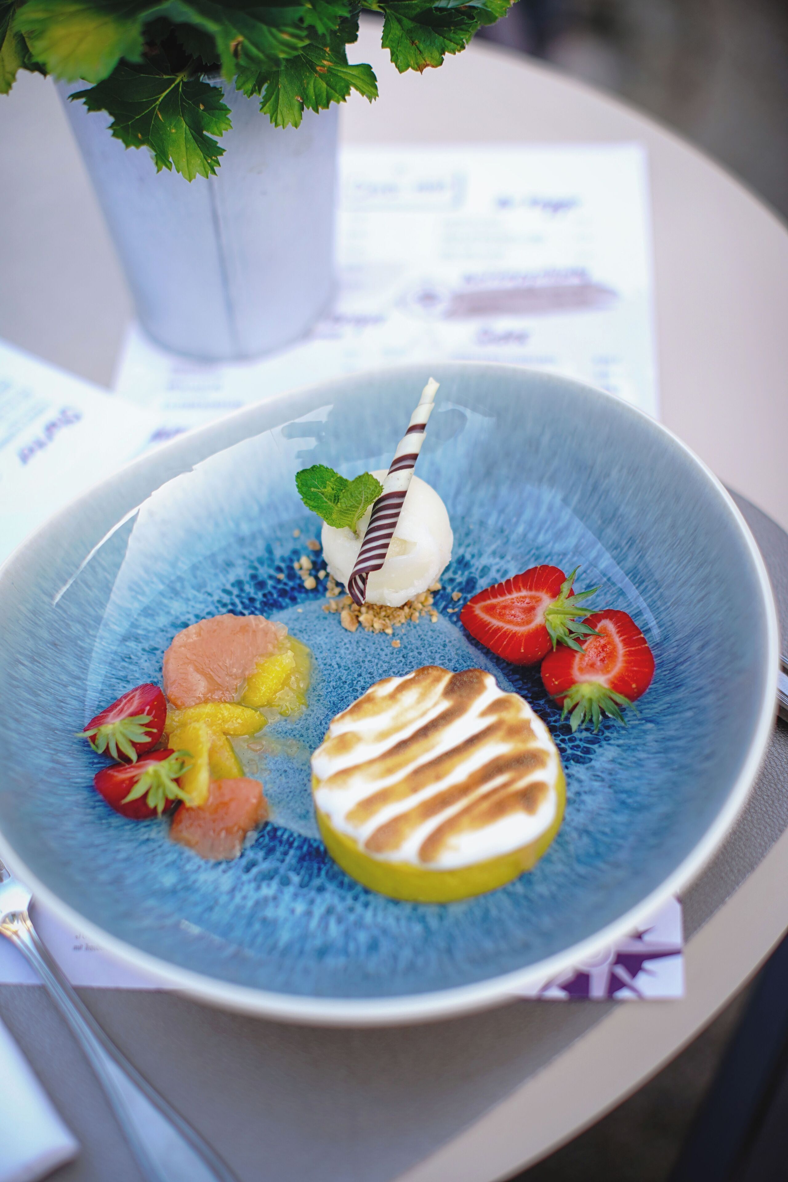 Une assiette de dessert garnie de divers fruits et de quelques feuilles de menthe.