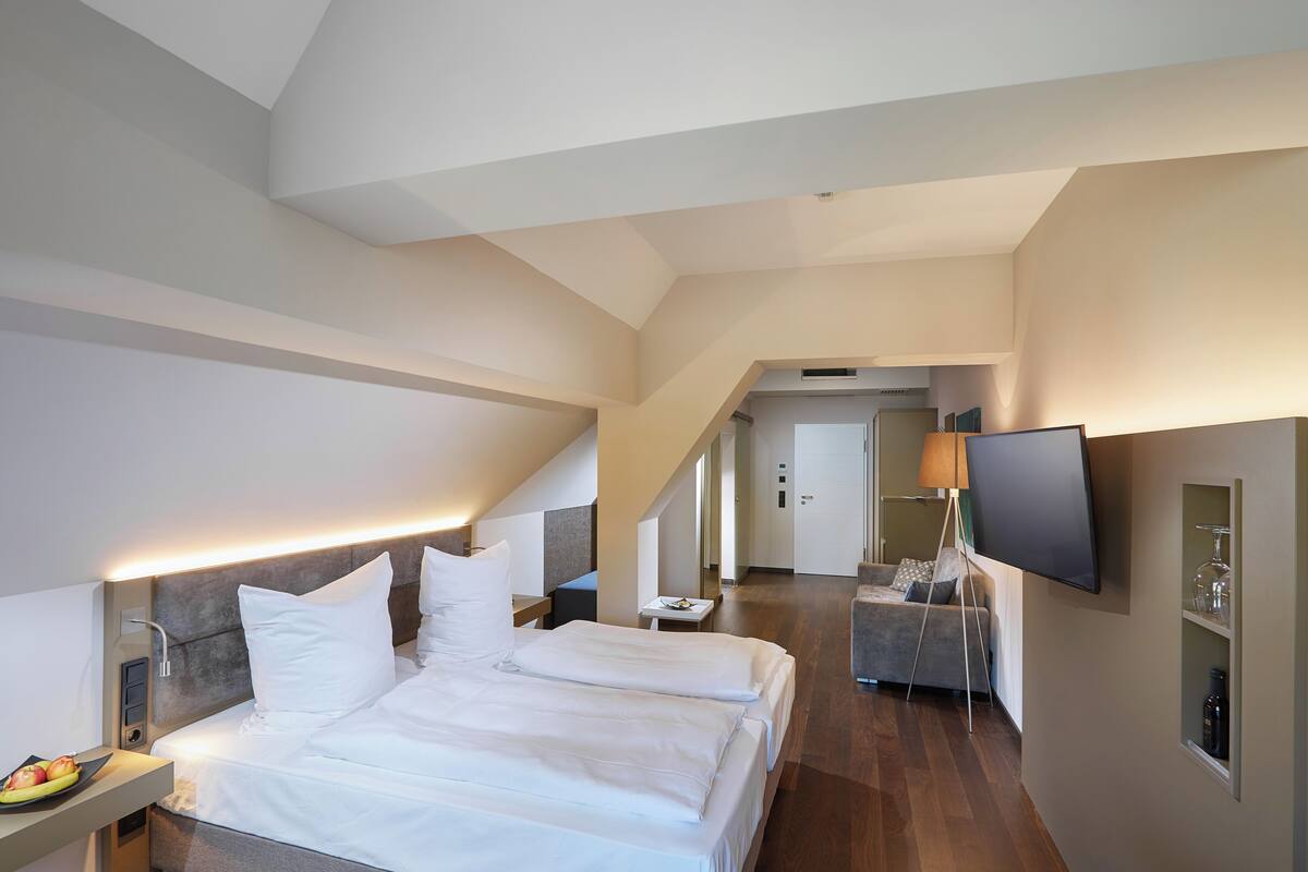 Ein Hotelzimmer mit einem großen Bett, Nachttischen, einem Fernseher und einem Schreibtisch mit Lampe.