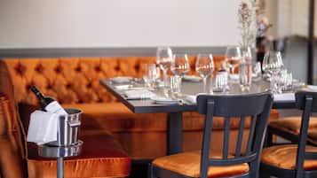 Un comedor con una banca de madera, una mesa dispuesta con copas de vino, platos y cubiertos.