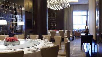 A modern dining area with round tables, chairs, and a large chandelier.
