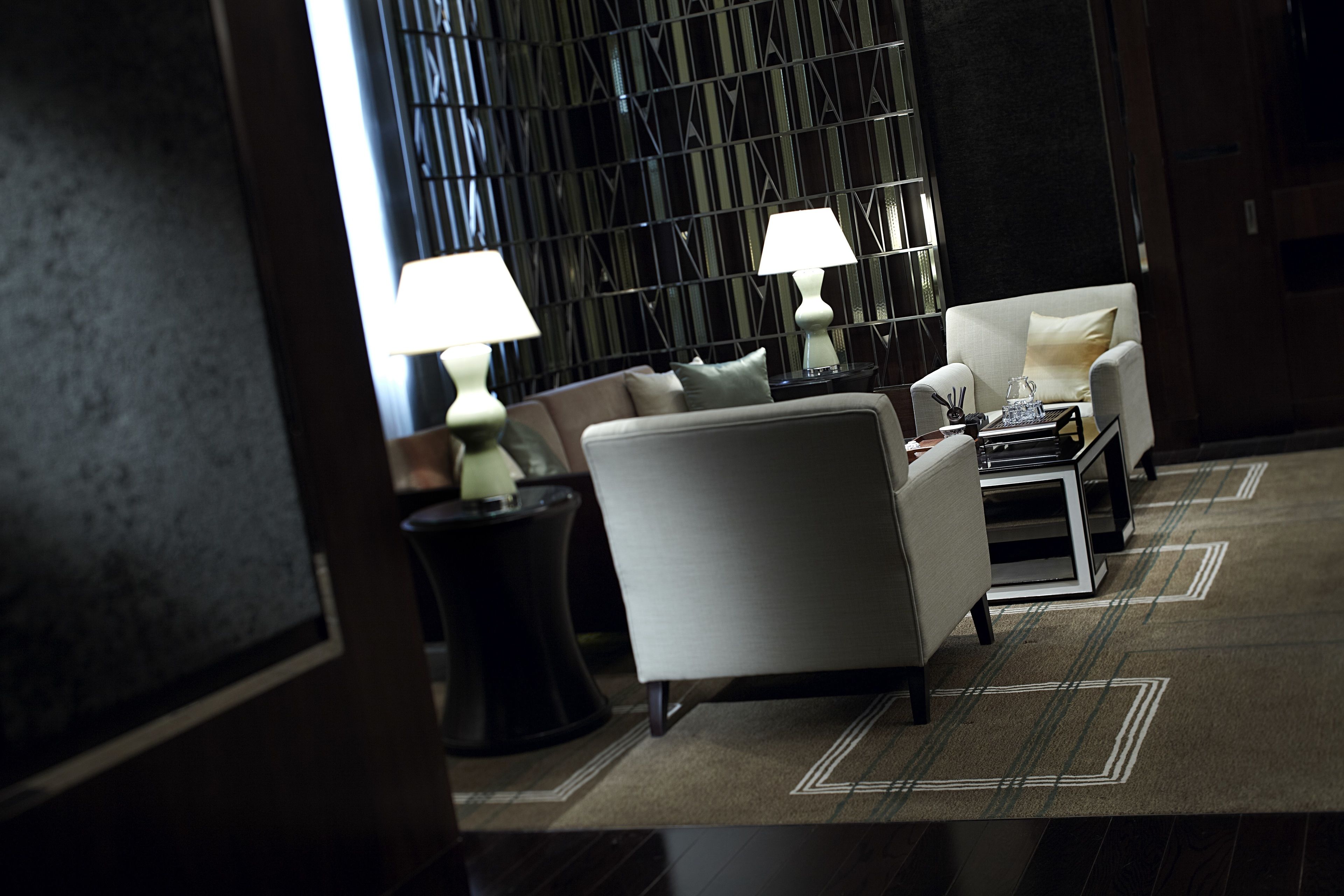 A modern hotel lobby with a sofa, armchairs, and a coffee table.