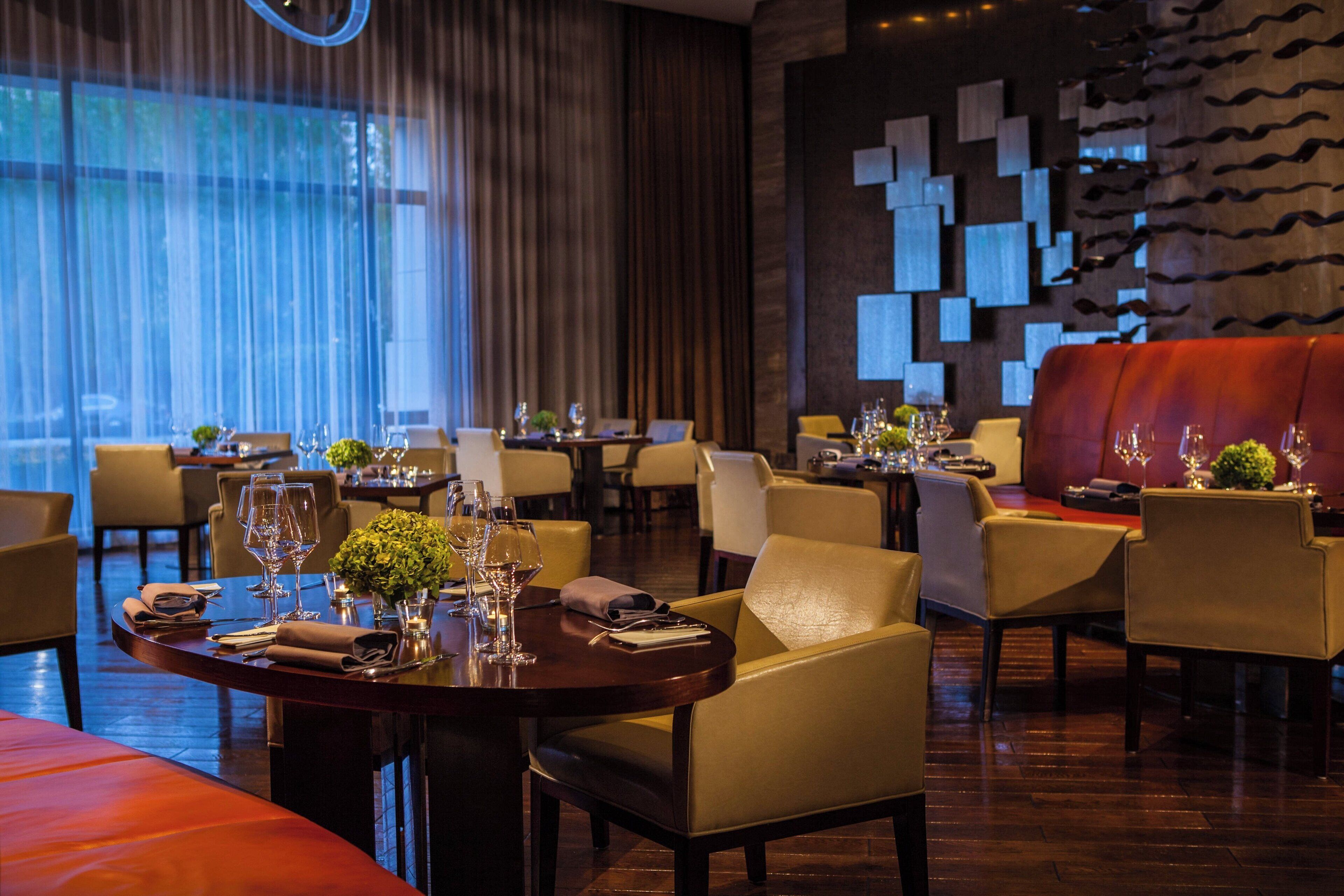 A restaurant with round tables, chairs, and a red sofa.