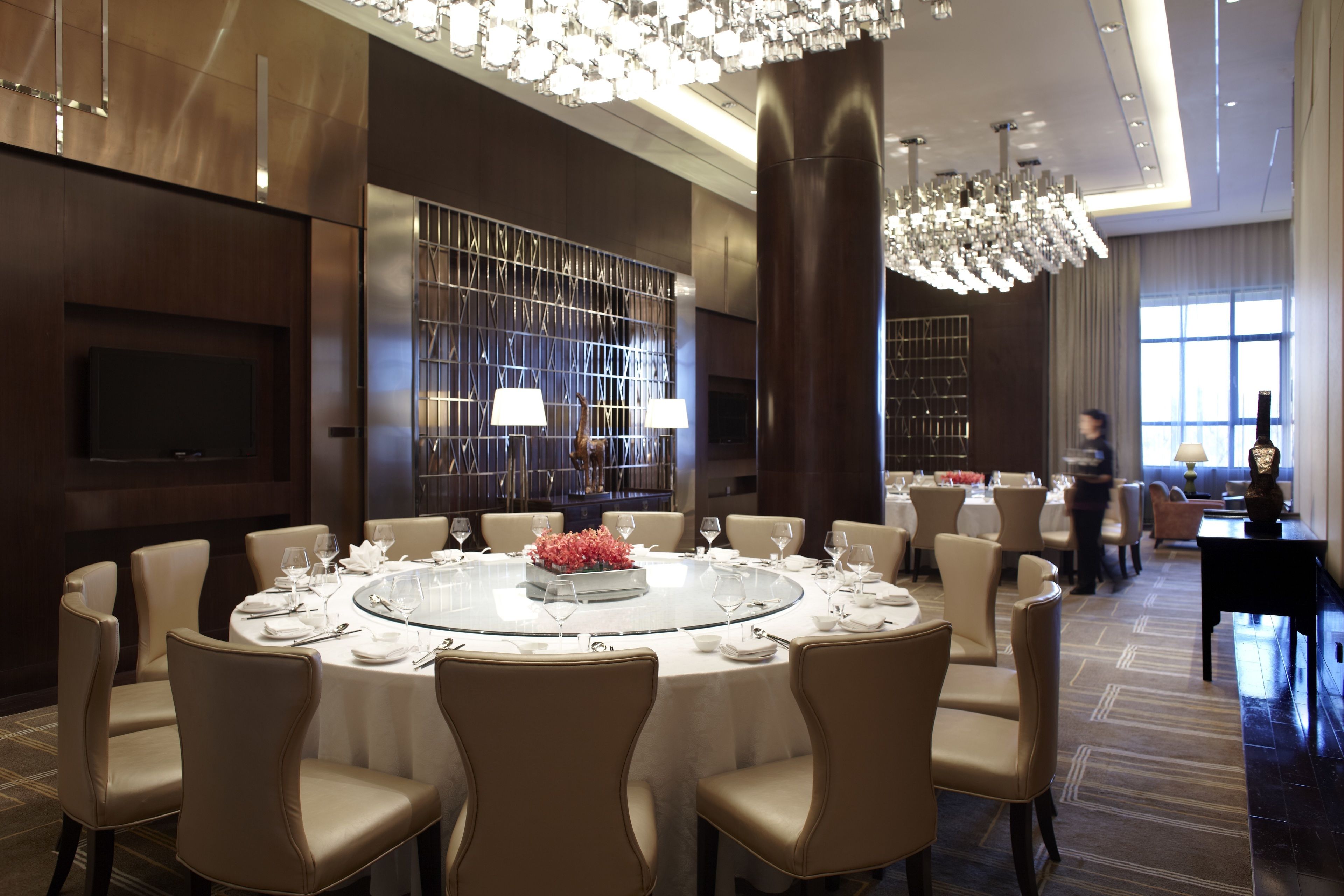 A spacious conference room with a round table, comfortable chairs, a large chandelier, and a modern interior design.