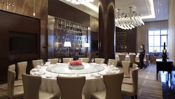 A spacious conference room with a round table, comfortable chairs, a large chandelier, and a modern interior design.