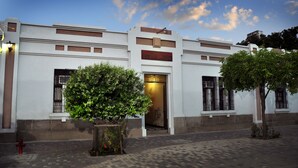 A building with a large entrance, a potted plant, and a fire hydrant. - Hotel Bahia Blanca (Santa Marta)