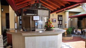 A hotel reception area with a check-in counter, a flower arrangement, and a tiled floor. - Hotel Bahia Blanca (Santa Marta)