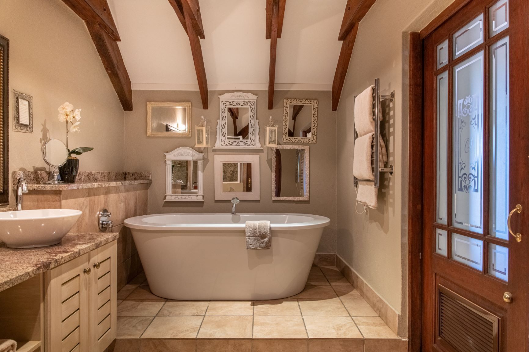A bathroom with a freestanding bathtub, a sink, and multiple mirrors.