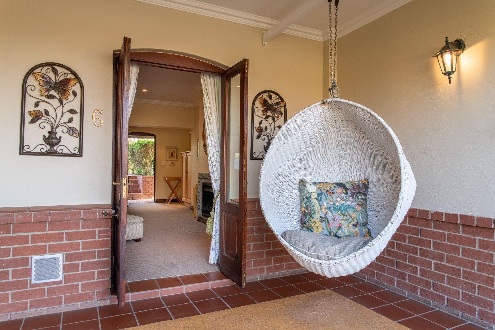 A room with a hanging chair, a fireplace, and a door leading to another room.