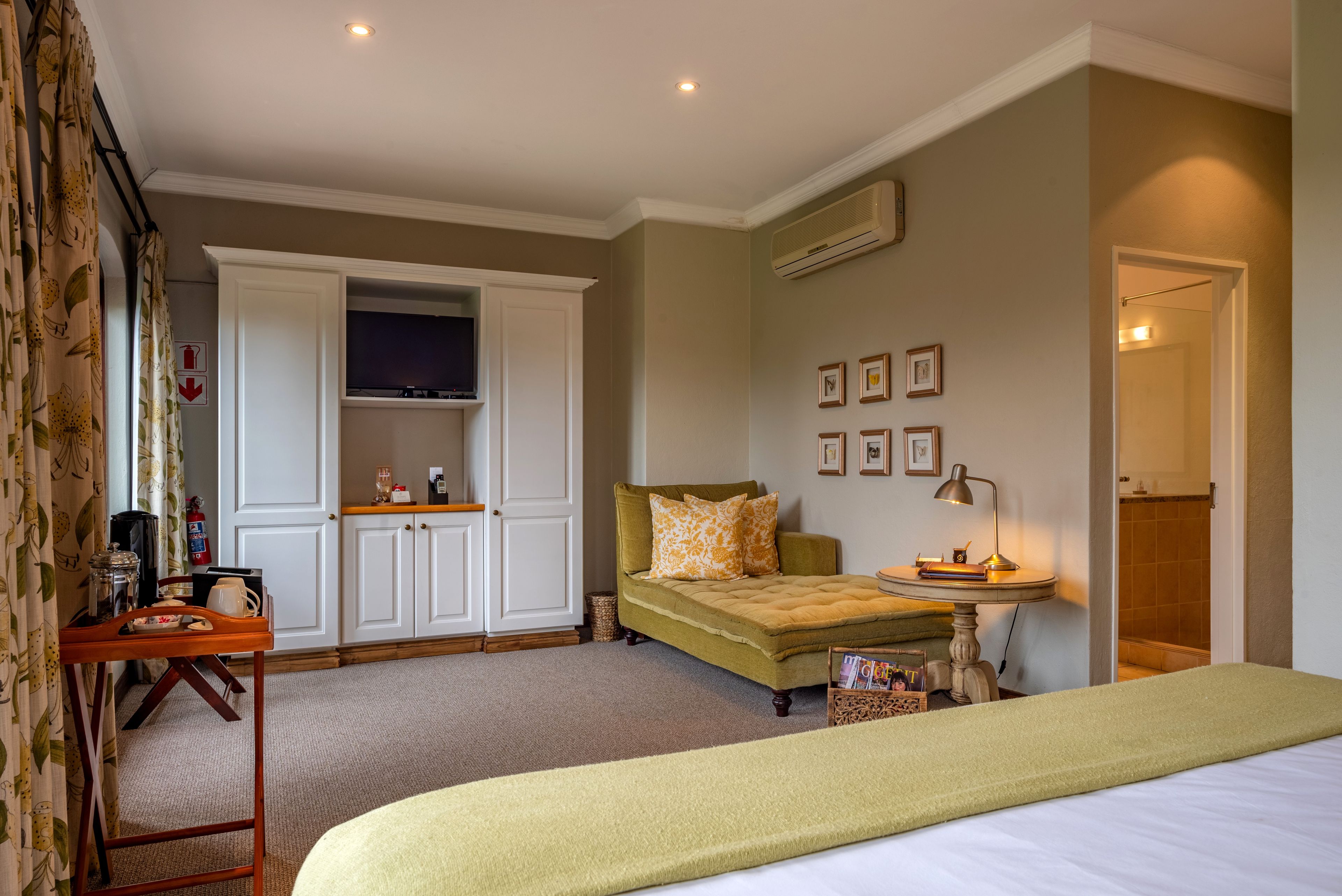 A bedroom with a bed, a desk with a lamp, a wardrobe, and a television.