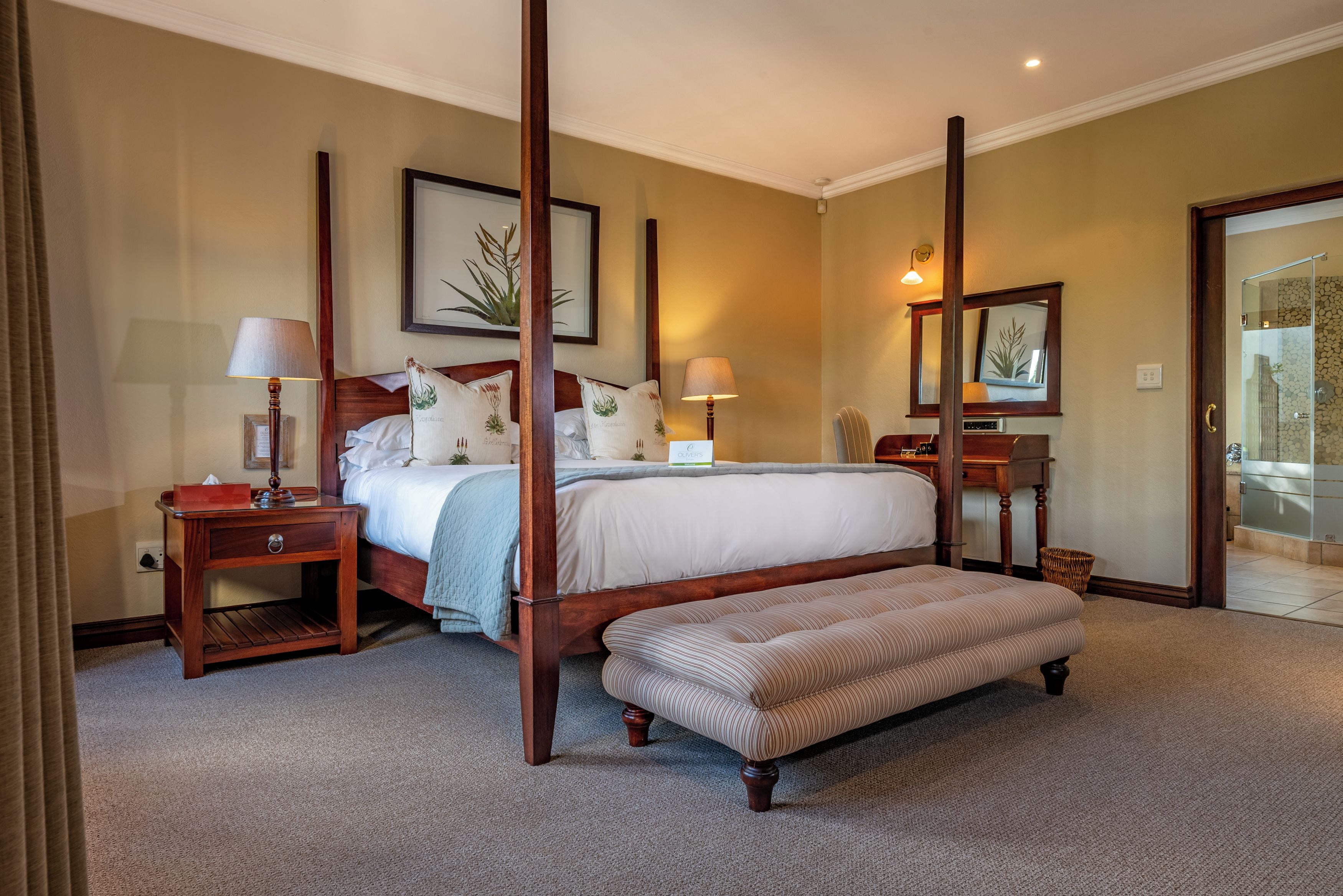 A four-poster bed with a wooden frame, a bench, and two bedside tables with lamps.