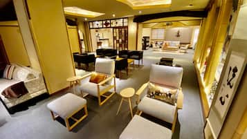 A spacious hotel lobby with multiple seating areas, including sofas and armchairs, and a traditional Japanese decor theme.