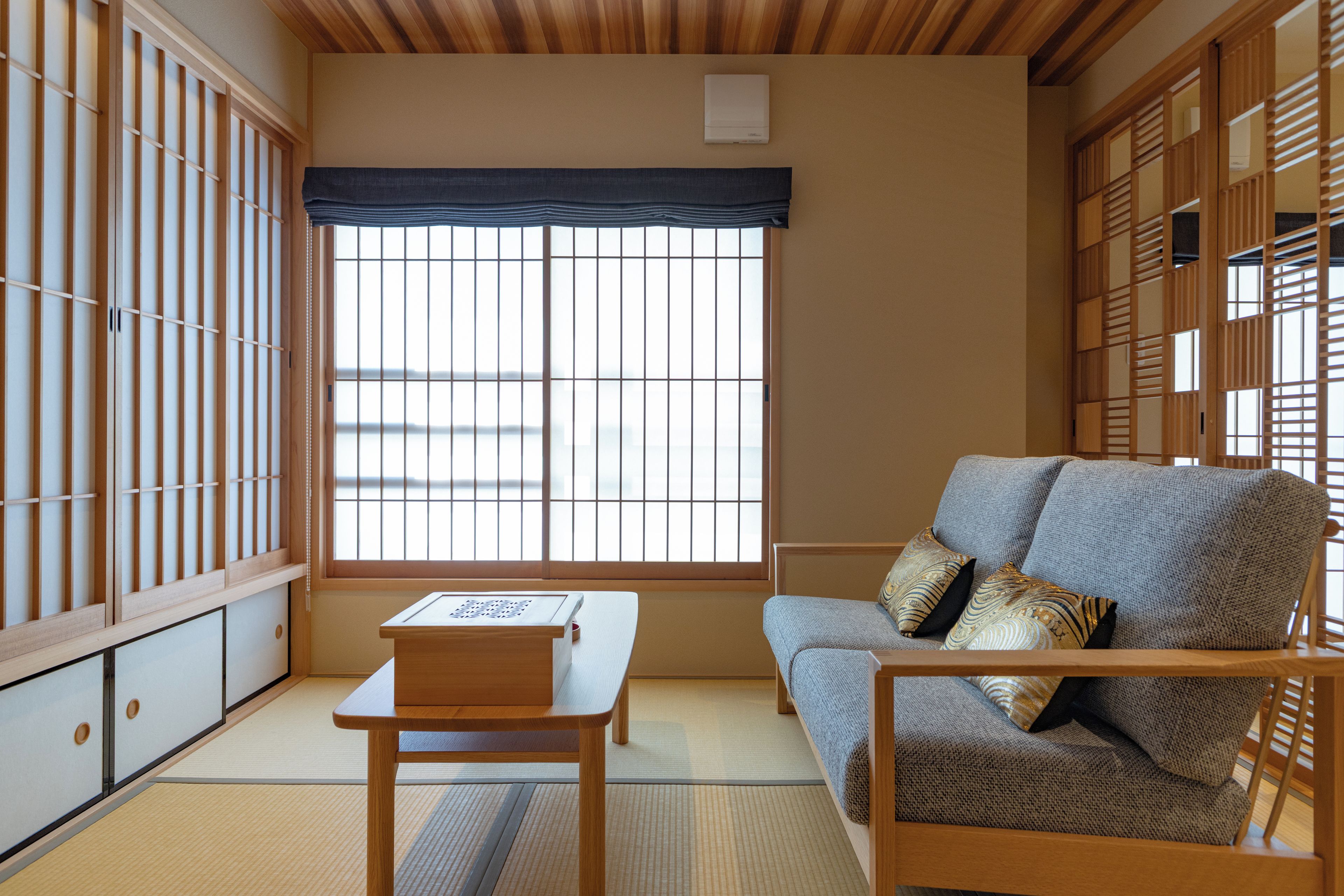 Une pièce de style japonais traditionnel, avec un sol recouvert de tatamis, une basse table en bois, un canapé avec des coussins et des paravents en papier de riz (shoji).
