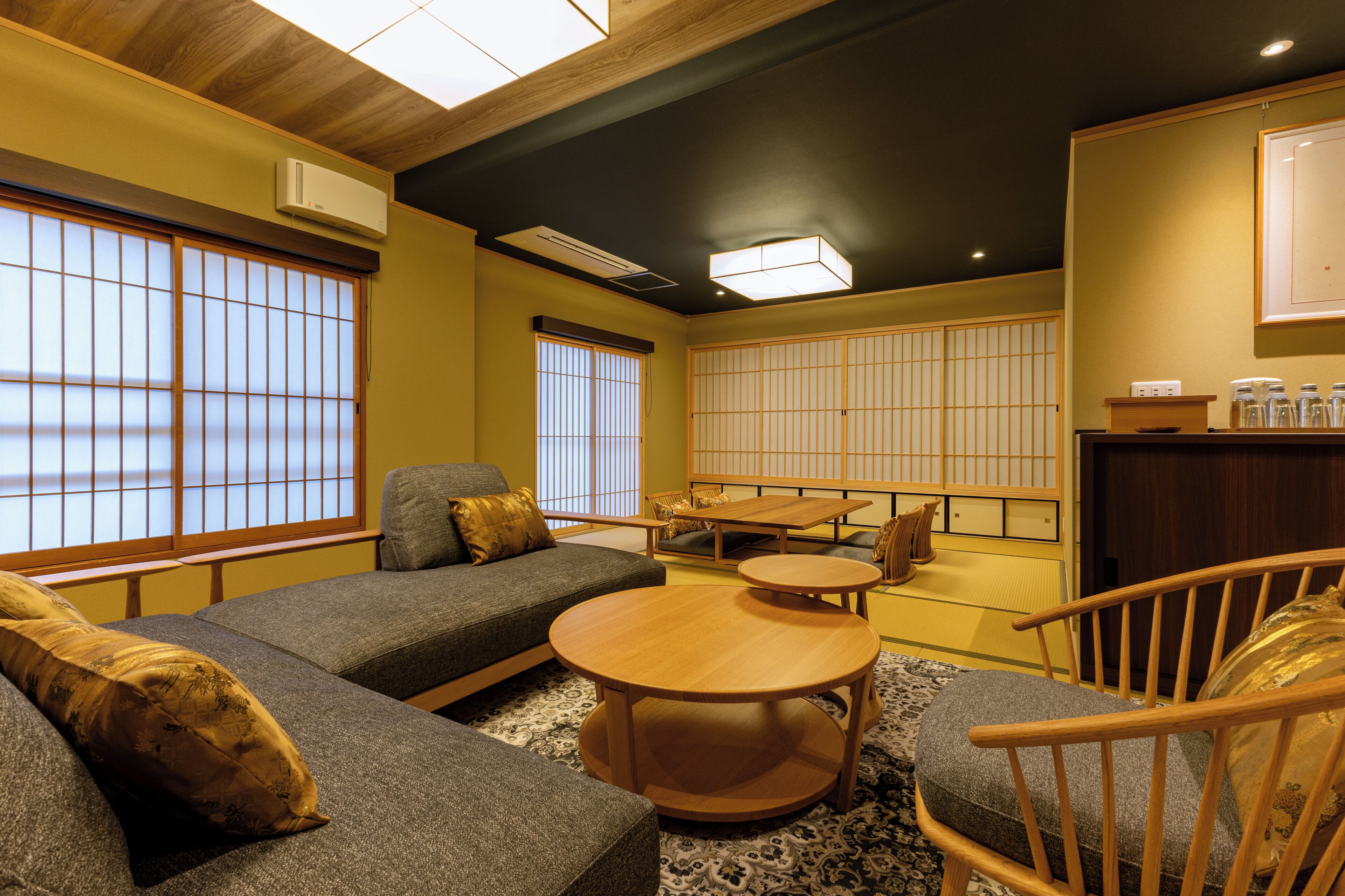 A traditional Japanese-style room with tatami flooring, a low wooden table, and a sofa with cushions.