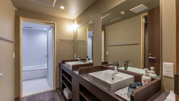 A modern bathroom with two sinks, a large mirror, and a shower area.