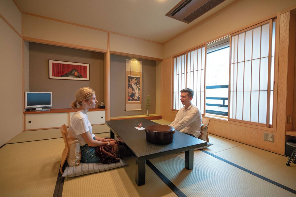 A traditional Japanese room with tatami flooring, a low table, and sliding doors.