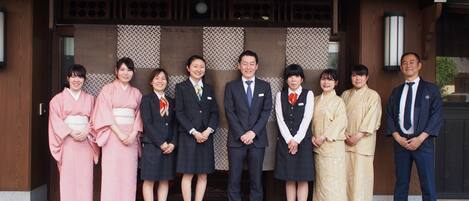 A group of people standing in front of a traditional building with a wooden facade and patterned wall decorations.