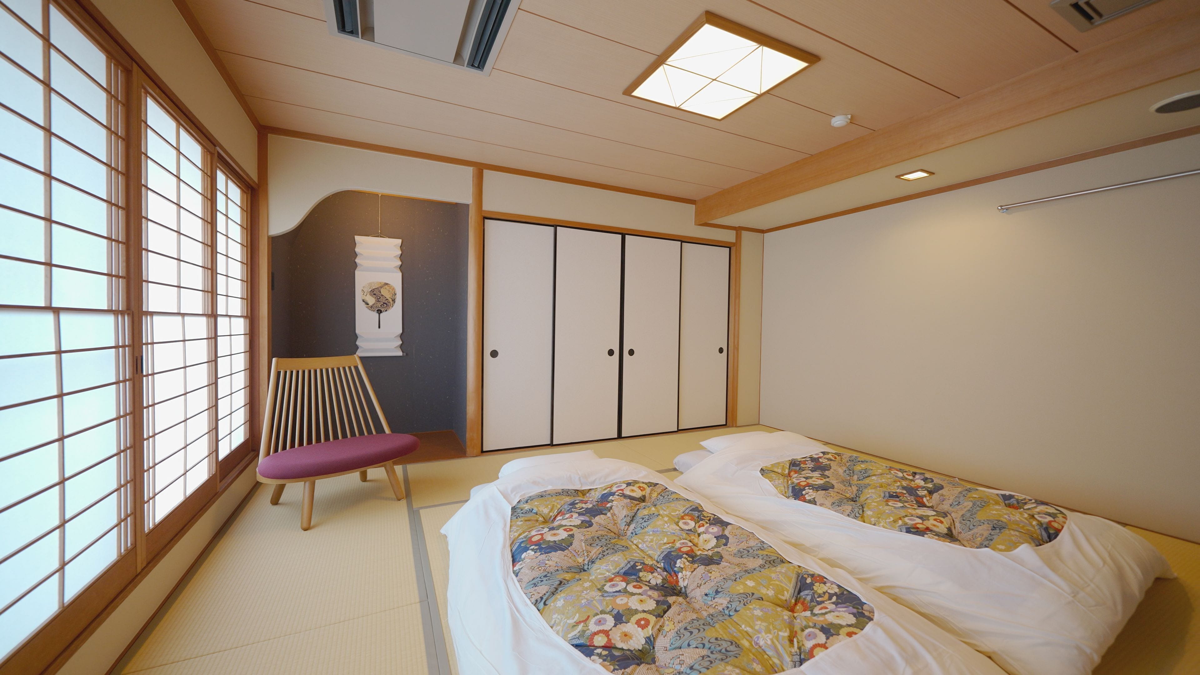 Perinteinen japanilaistyylinen makuuhuone, jossa on tatamimatto, futon-patja, liukuovet ja shoji-paperi- tai puukehysseinä.