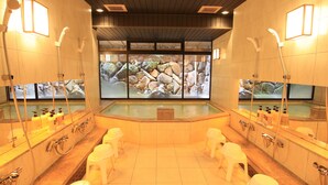 Et moderne spa med centralt boblebad, flere brusehoveder og et stort vindue med udsigt til klippeformationer.
