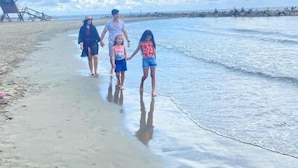 Escena de playa con una familia caminando por la orilla.