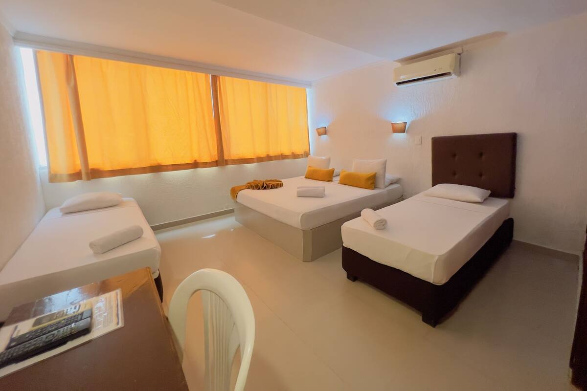 A hotel room with two single beds, a small desk, and a chair.