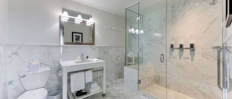 A modern bathroom with a white toilet, a vanity with a mirror, and a glass-enclosed shower area.