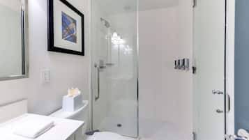 Une salle de bain moderne avec une douche à parois de verre, un lavabo blanc et un tableau encadré au mur.