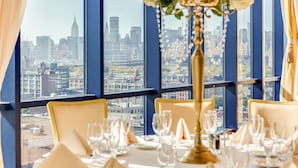 Mesa de comedor lista para una comida, con vistas a la ciudad a través de amplios ventanales.