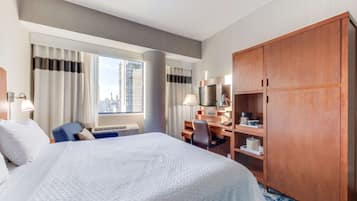 A hotel room with a large bed, a desk, a wardrobe, and a window with curtains.