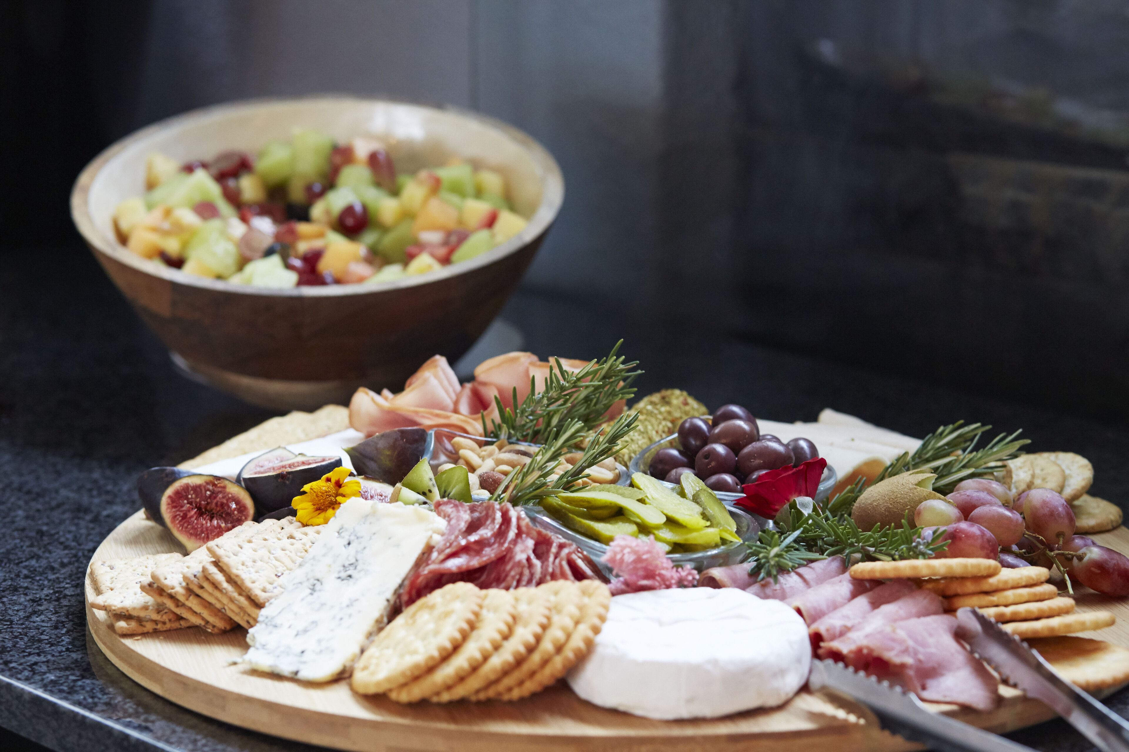 A charcuterie board with various cheeses, meats, crackers, and fruits.