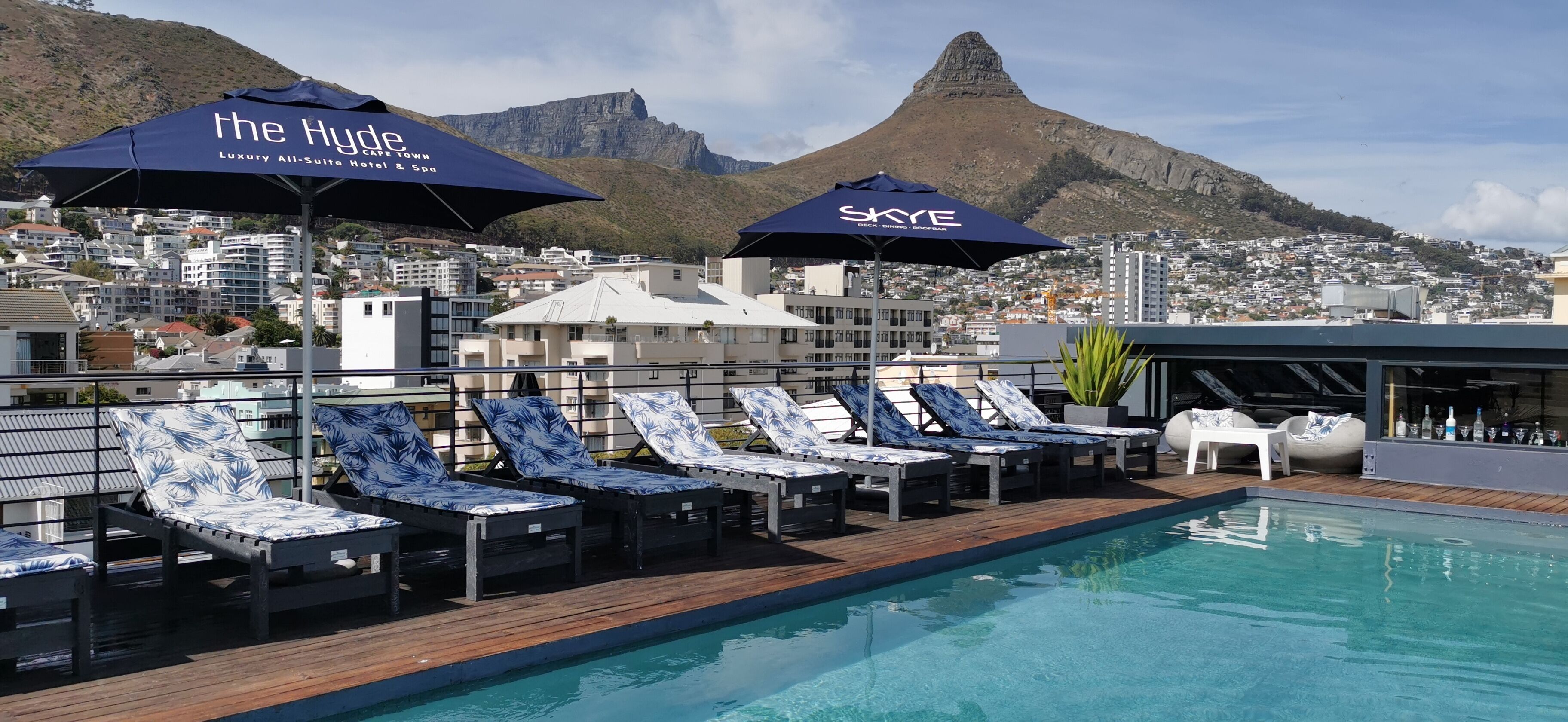 Una piscina al aire libre, sombrillas, sillones reclinables de piscina