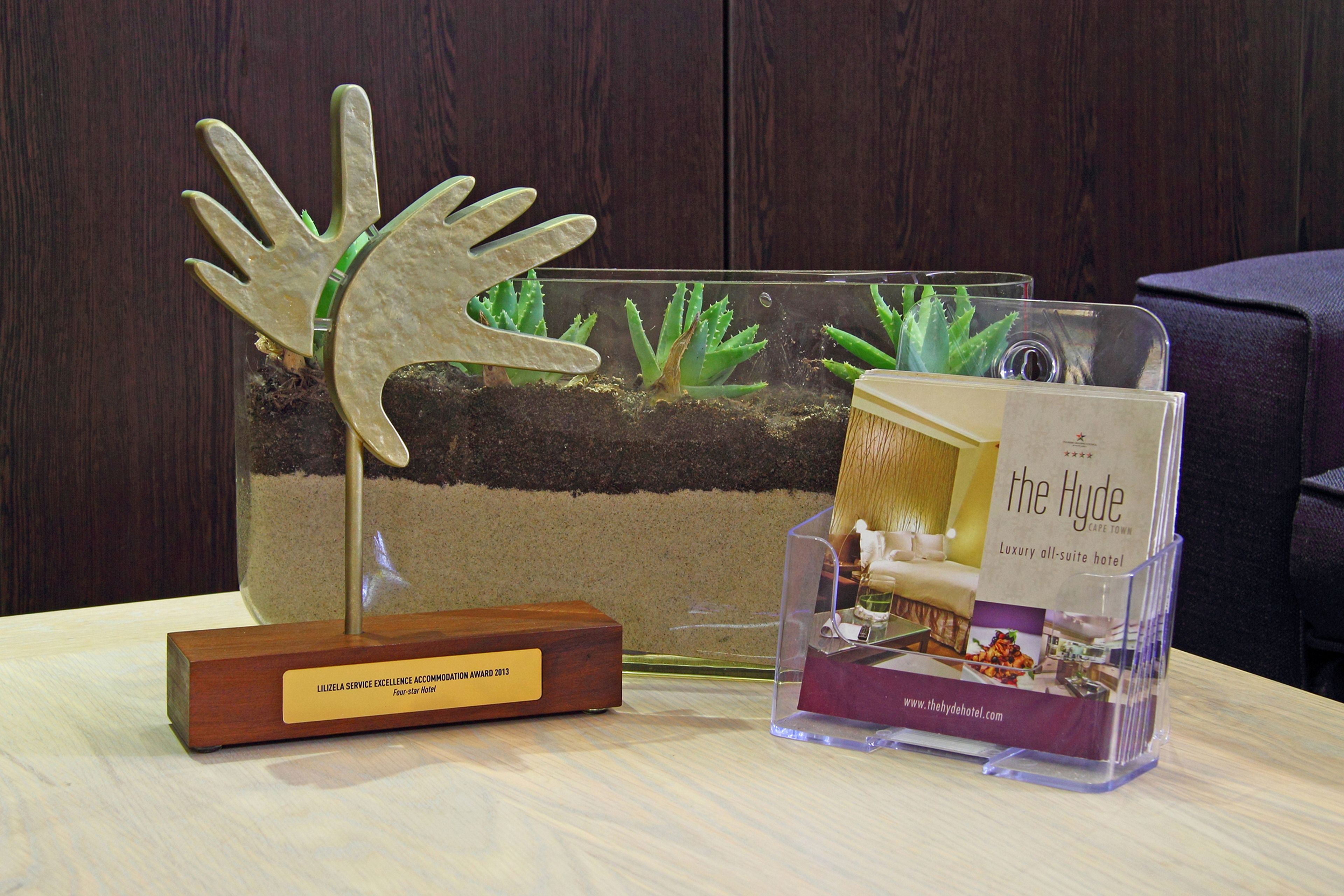 Une présentation comprenant un terrarium en verre, une plaque en bois et une brochure pour l’hôtel de luxe The Hyde, qui ne propose que des suites.
